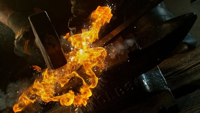 Close-up of blacksmith forging glowing hot iron on anvil with flying sparks