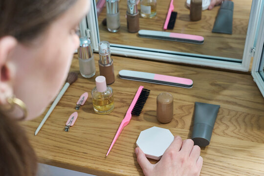 Teenage girl with OCD, carefully arranging make up items on dressing table in bedroom