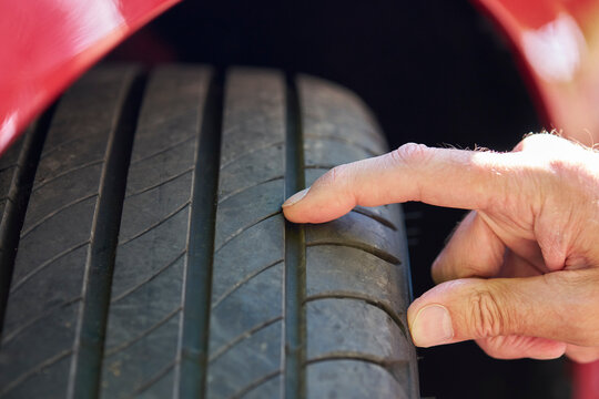 Close up of man checking  tyre tread depth on car