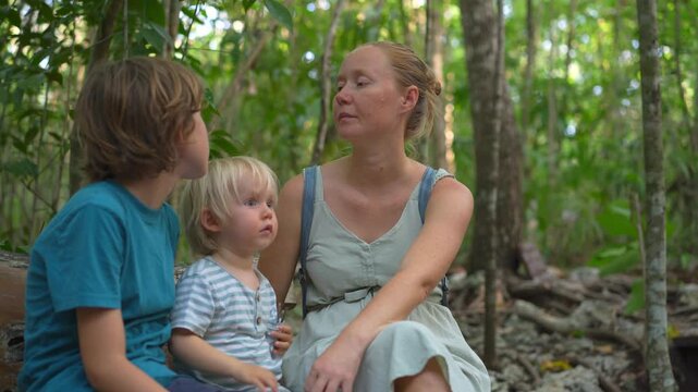 Young mom spending quality time with her two sons in a lush green park, enjoying nature, laughter, and joyful family bonding moments outdoors.