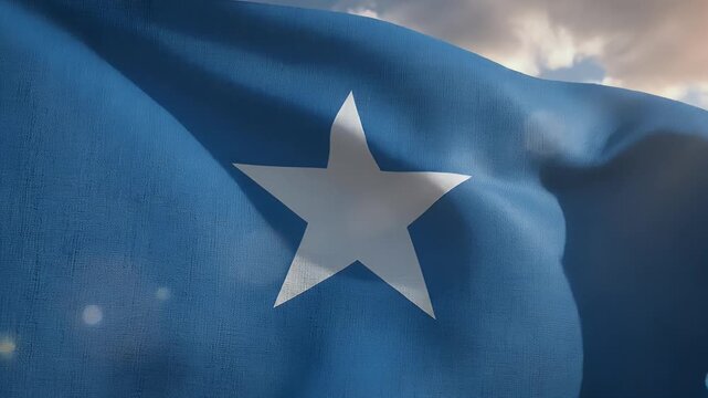 A blue flag with a white five-pointed star ripples against a cloudy sky at sunset