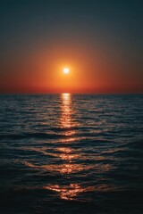 Fototapeta premium Sun sets over calm ocean, casting golden glow across water