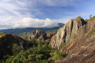 Fototapeta premium Stunning view of sharp, jagged rock formations surrounded by lush green hills under a cloudy sky
