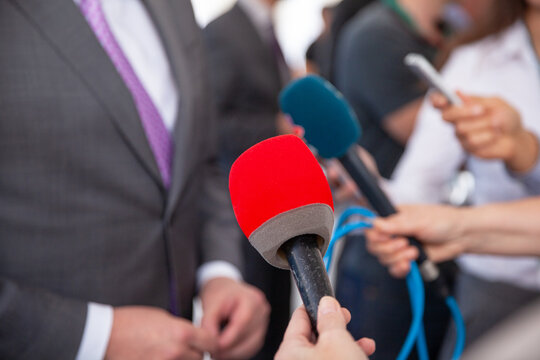 Journalists holding microphones interviewing businessman at press event, media coverage concept, public relations, news reporting, communication and corporate interview in professional setting
