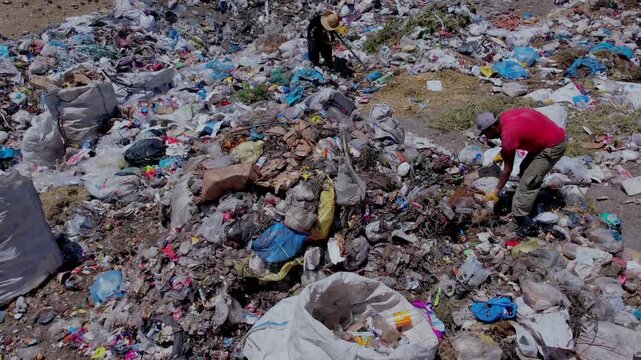 Aerial view of people collecting waste in a landfill with dense garbage accumulation. Scene highlights environmental pollution, waste management, recycling, and human labor.