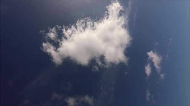 Bright white clouds drift across a deep blue sky on a sunny day