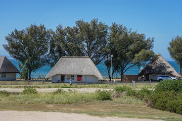 South Africa,Garden Route,Traditional thatched-roof houses near a coastal area with trees and clear blue sky © SHUNJI ZHOU