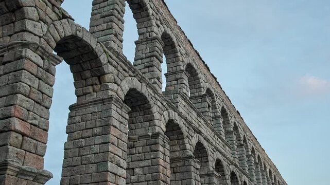 Perspective view of the Roman aqueduct in Segovia, Spain, highlighting repeating stone arches, depth and symmetry in ancient architecture and engineering.