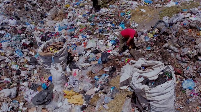 Aerial view of people collecting waste in a landfill with dense garbage accumulation. Scene highlights environmental pollution, waste management, recycling, and human labor.