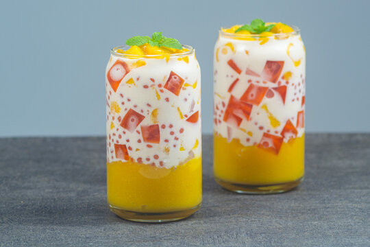 Delicious mango sago dessert with fresh mango, jelly, pearls, and mint leaves in a glass. Delicious and refreshing tropical fruit for summer