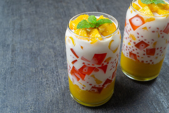 Delicious mango sago dessert with fresh mango, jelly, pearls, and mint leaves in a glass. Delicious and refreshing tropical fruit for summer
