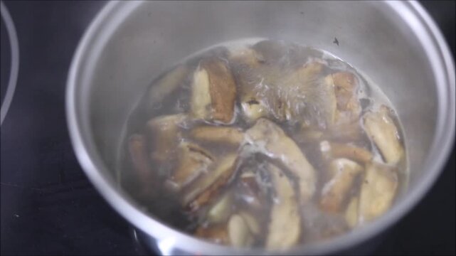 Slicing shiitake mushrooms and onions in a pot with a wooden spoon