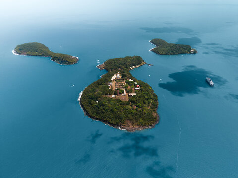 Aerial view of the lush Salvation Islands surrounded by turquoise ocean water and a large ship in Iles du Salut, French Guiana.