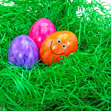 Ostereier im Gras mit lustigem Gesicht