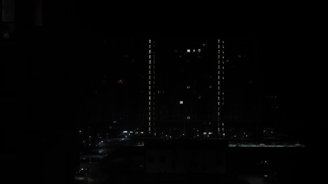 Timelapse at night, multi-storey building in the city. Turning off the lights in the house