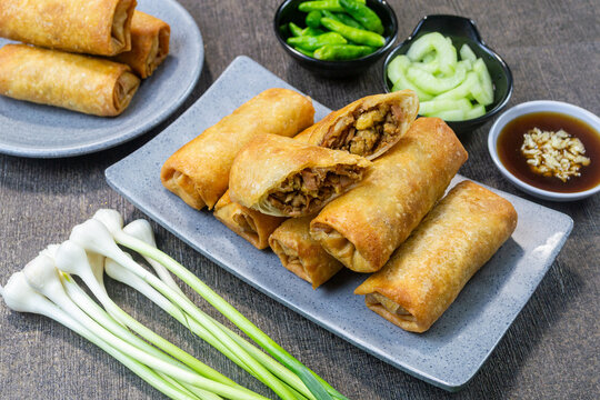 Indonesian Lumpia Semarang fried spring rolls on a grey plate with dipping sauce and fresh green bird's eye chilies