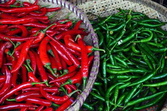Large red chilies in a winnowing basket and large green chilies in a winnowing basket. Tampah. Chilies sold in the market