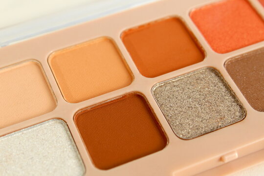 A palette of multi-colored light eyeshadows lies on a white background.