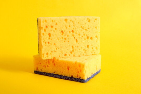 Several porous dishwashing sponges lie on a yellow background.