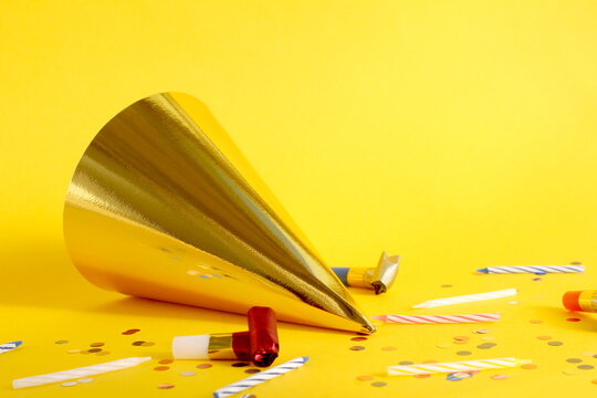 On a yellow background lies a festive hat with festive accessories.