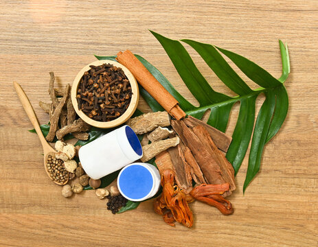Flat lay of traditional Thai herbs and aromatic ingredients used in herbal inhaler and natural remedies on wood.
