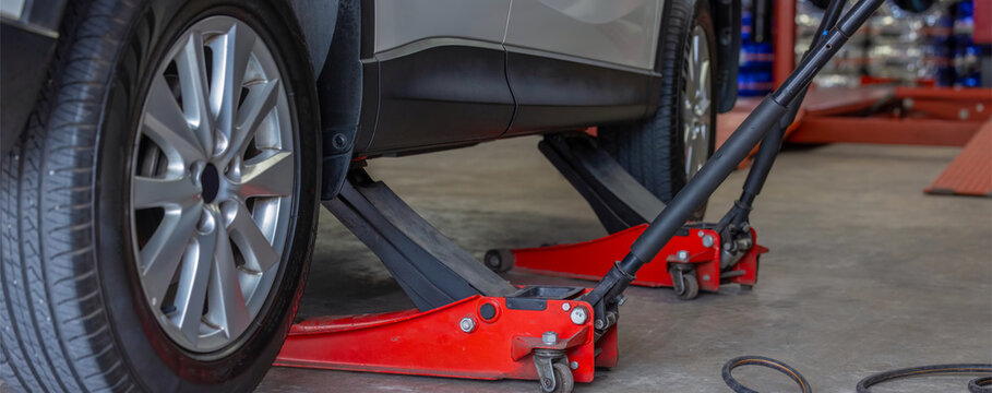 Car lifted by scissor jack. Auto mechanic changing wheel