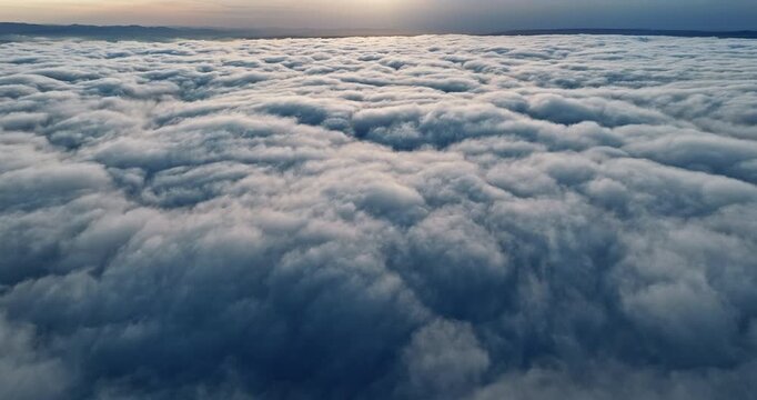 Top down aerial perspective dense clouds summer sunset. Drone shot high above white cloud cover golden hour light. Heavenly nature background majestic atmosphere freedom travel concept scene.