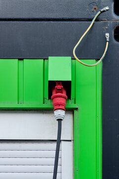 Industrial CEE Power Plug Connected to Green Metal Container Wall