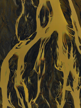 Aerial view of abstract patterns of a glacial river delta with golden water flowing through dark volcanic sand in Iceland.