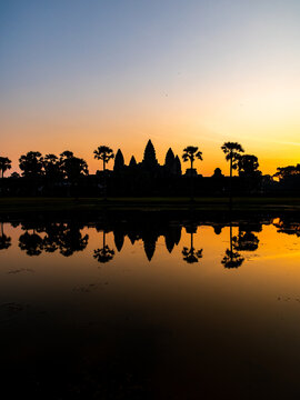 View of the serene silhouette of Angkor Wat mirrored in the still waters at sunset, a timeless landscape, Siem Reap, Siem Reap Province, Cambodia.