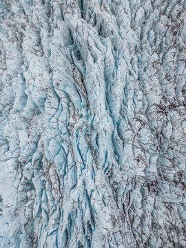 Aerial view of glacier crevasses with deep blue ice ridges and textured frozen surface Iceland.