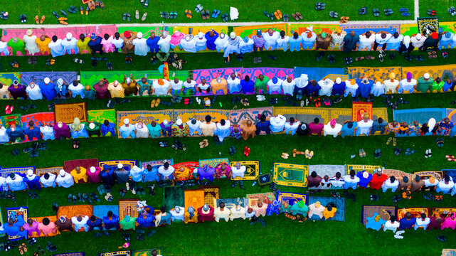 Lagos, Nigeria - 20 March 2026: Aerial view of rows of vibrant prayer mats laid out on lush green grass, adorned with the scattered shoes of worshippers during prayers.