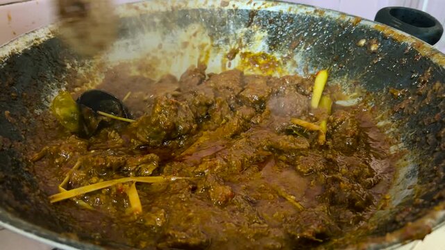 The process of cooking beef rendang with typical Indonesian spices.
