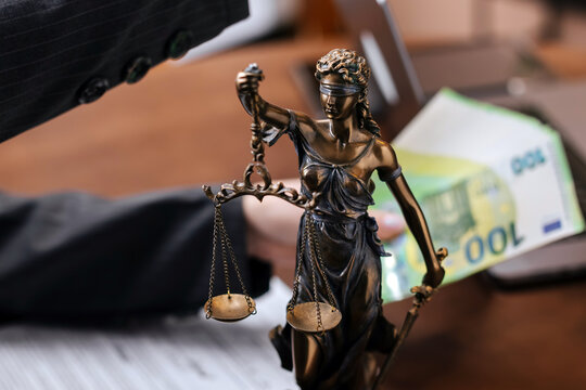 Hand passing cash across lawyer's desk. Corruption, payment and legal agreement concept.
