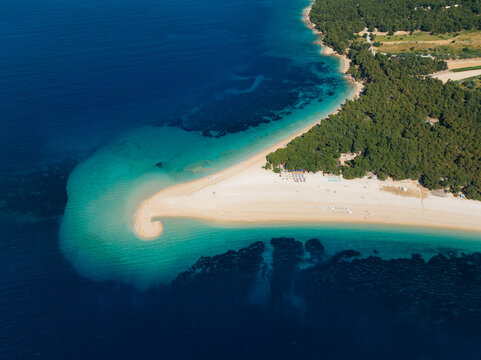 Aerial view of Zlatni Rat, a mesmerizing golden horn beach with turquoise waters meeting the lush green forest, Bol, Split-Dalmatia County, Croatia.