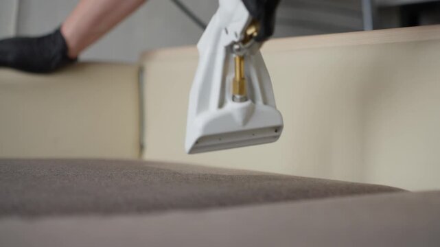 Operator Utilizes Steam To Clean Fabric Carefully. Gloved Hand Maneuvers Hose For Detailed Fabric Cleaning. Deep Cleaning Upholstery With Steam Wand While Preserving Fabric Integrity Carefully