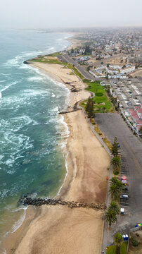 Aerial view of the coastline with sandy beaches, crashing waves, and urban development along the shore in Swakopmund, Erongo Region, Namibia.