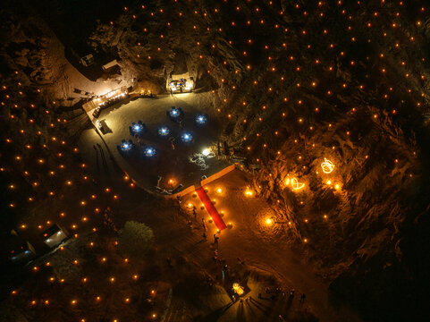 Aerial view of an elegant outdoor dinner setup at night with a red carpet and glowing lanterns scattered across the rocky desert landscape in Namibia.