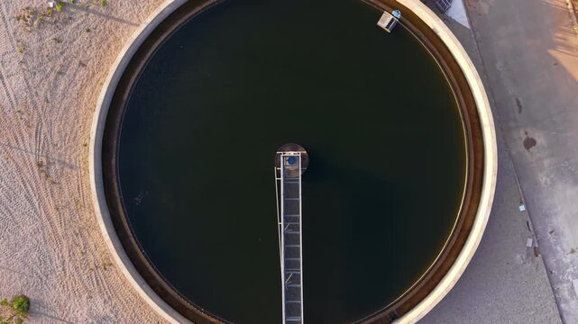 Top-down view of circular clarifier with radial scraper bridge, sludge settling zone, peripheral weir, and inlet feed for sedimentation in wastewater treatment process
