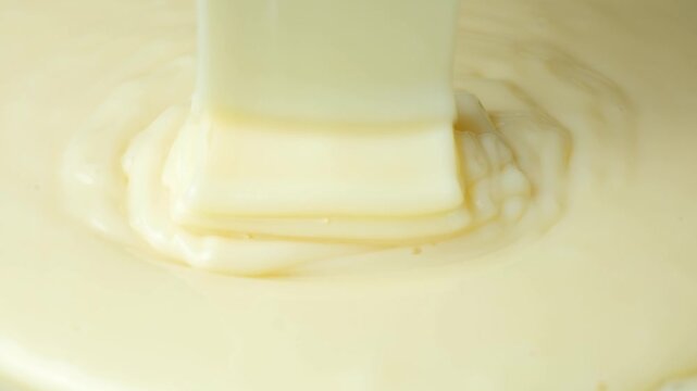 Glossy white condensed milk dripping in elegant folds and swirls.