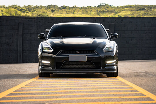Black Nissan GT-R full front view centered, High performance sports car outdoors on empty road