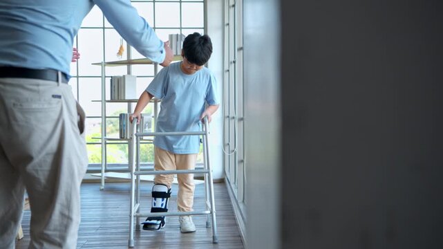 Young boy practicing walking with mobility aid under parental supervision in rehabilitation clinic