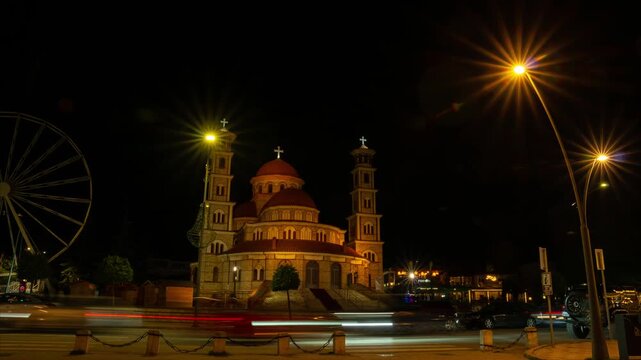 A cinematic evening timelapse of the Resurrection of Christ Cathedral in Kor&ccedil;&euml;, Albania, captured from the city's pedestrian zone as evening lights illuminate the square and historical architecture.
