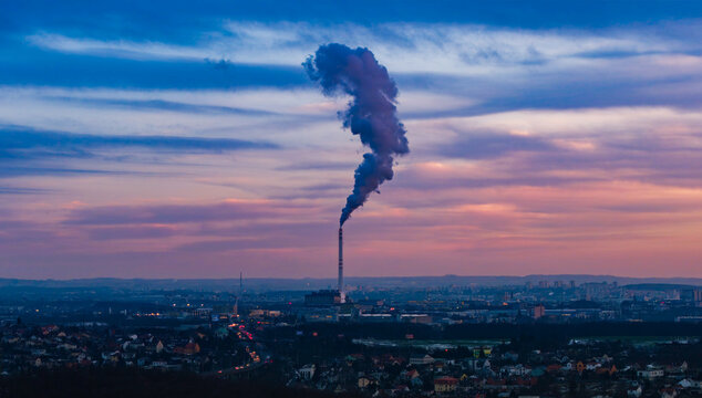 Aerial view of plume rising from the incinerator against a backdrop of the city skyline painted with hues of dawn, Praha 9, Hlavni mesto Praha, Czechia.
