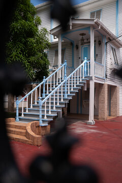 View of a traditional colonial wooden house with a blue and white facade and an elegant external staircase in Georgetown, Guyana.
