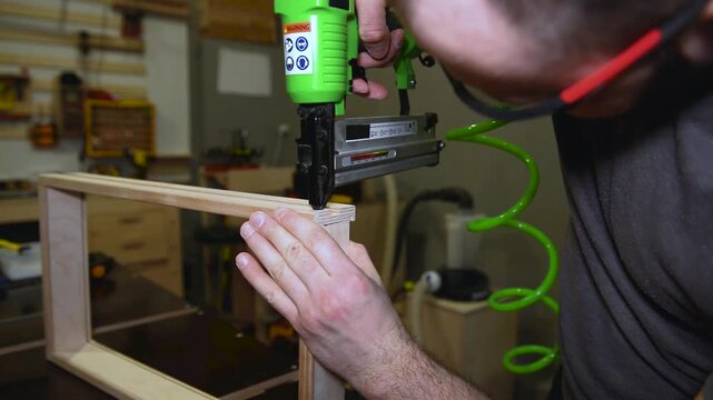 Pneumatic brad nailer securing to fasten the wooden planks, Nail gun drives fasteners smoothly, showing craftsmanship and professional home renovation work.
