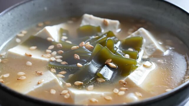 Close-Up of Steaming Miso Soup With Tofu, Wakame Seaweed, and Sesame Seeds in a Bowl