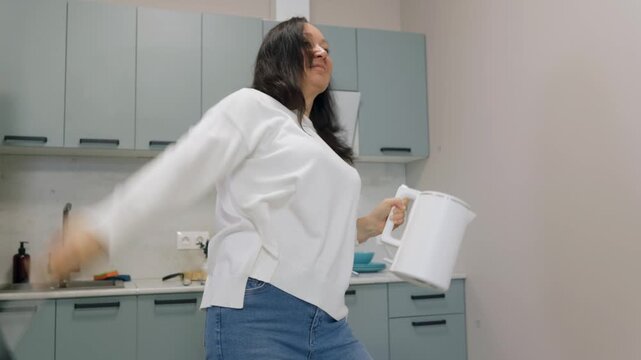 White woman playing kettle as drum in modern kitchen, holding ladle and kettle, improvising percussion, casual jeans and sweater, countertop and cabinets, upbeat domestic jam, playful