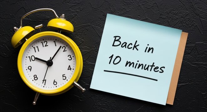 Yellow alarm clock with sticky note, Back in 10 minutes handwritten message, time management and break concept on black background