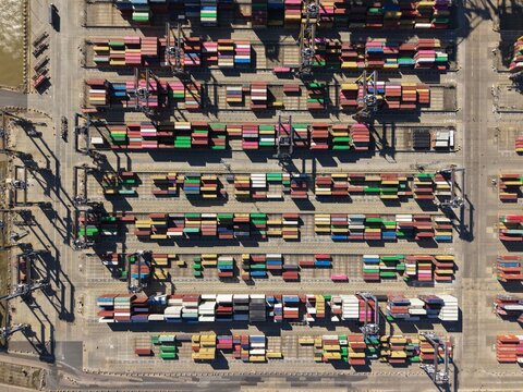 Aerial view of a symphony of stacked shipping containers in an array of colors and textures, creating a geometric pattern at The Dock, Port of Felixstowe, Felixstowe, United Kingdom.